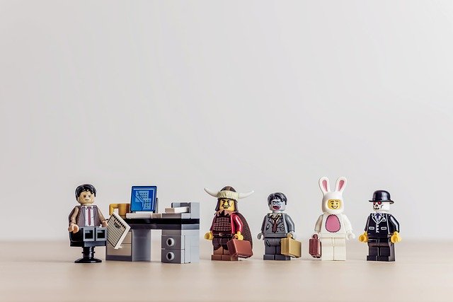 Lego characters lining up to a desk and office.