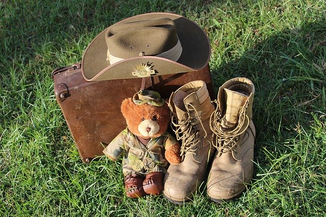 Army boots, hat and small teddy bear in army attire. 