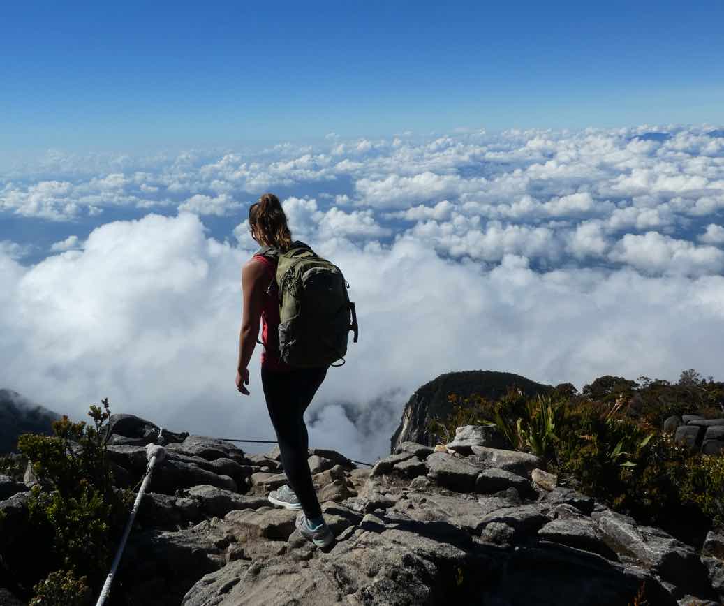 Image of Dr. Ann Herbst on a rock cliff above the clouds