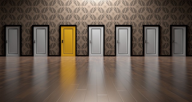 Yellow door in a hallway of identical white doors.