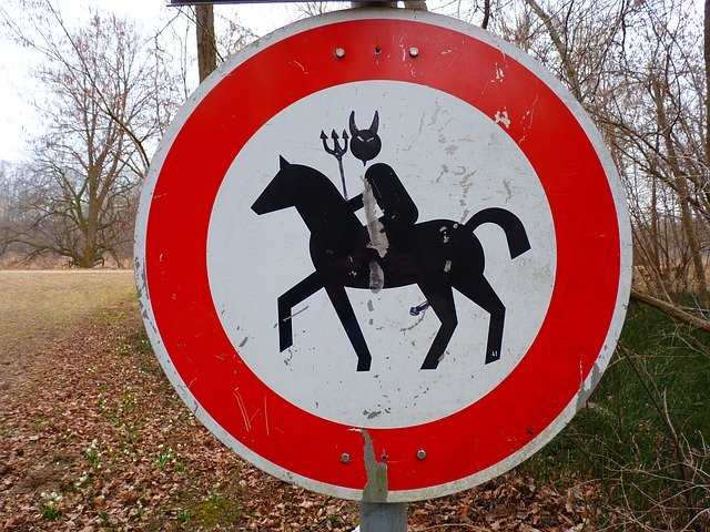 stop sign with man riding horse, modified to have devil horns and spike