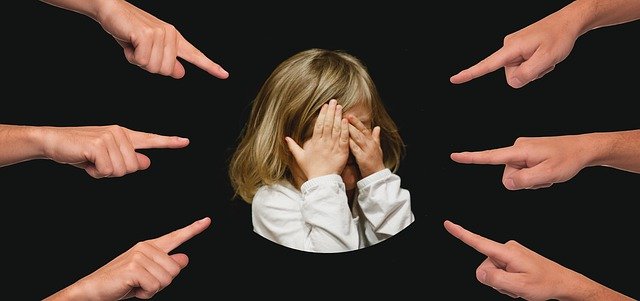 girl covering face with multiple fingers pointing