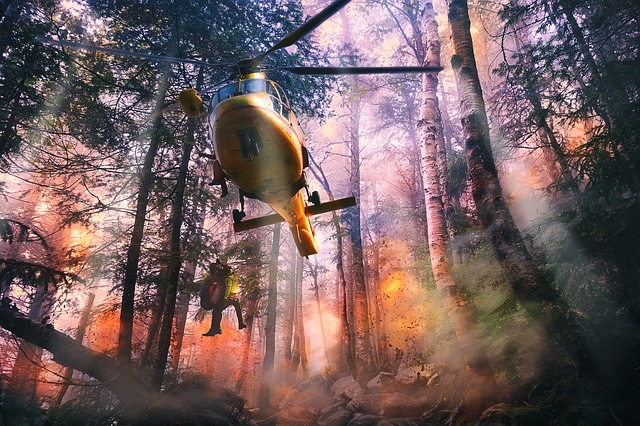 Helicopter flying through burning forest with fire-fighter and civilian hanging.