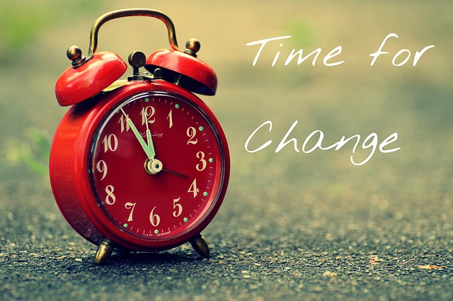 Clock in front of blackboard with 'Time for Change' written. 